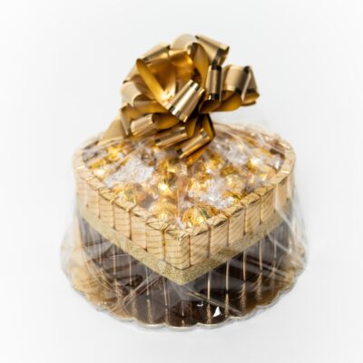 Darčekový kôš srdce s pralinkami Lindor a čokoládami Merci, zlatá stuha, biele pozadie.